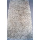 An Ultimate Rug Company Embassy pattern shag pile style rug, in cream, label verso, 136cm x 82cm.