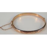A 9ct gold hollow bangle, with a part engine turned gate clasp, 7cm wide, 5.5g.