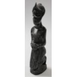 A 20thC ebonised African hardwood tribal figure, of a lady in a crouched position with hands to