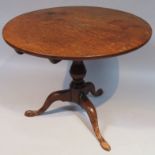 An 18thC oak tripod table, the plain circular top raised on a gun barrel support terminating in