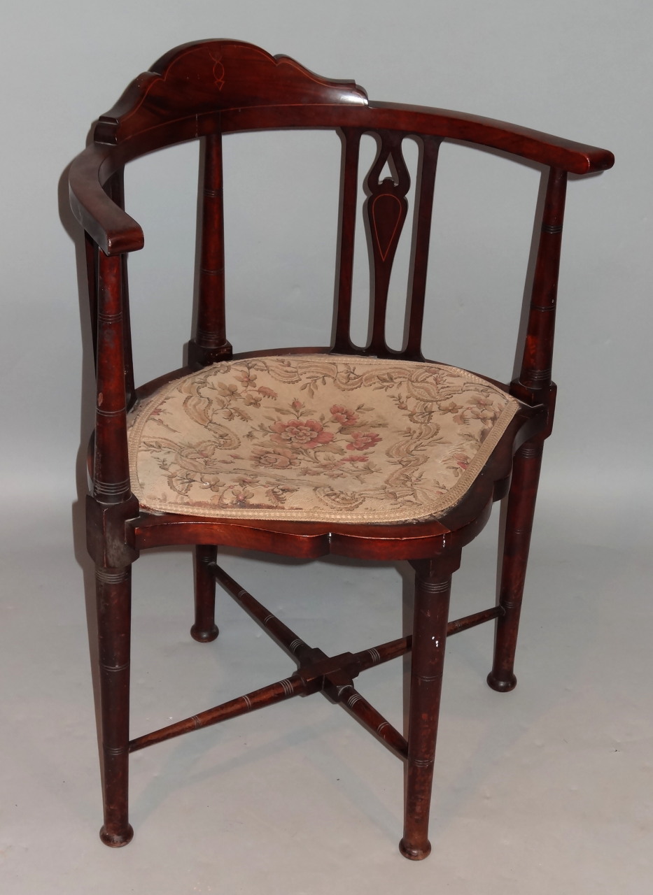 An Edwardian mahogany and boxwood strung corner chair, with a shaped top above a cylindrical and