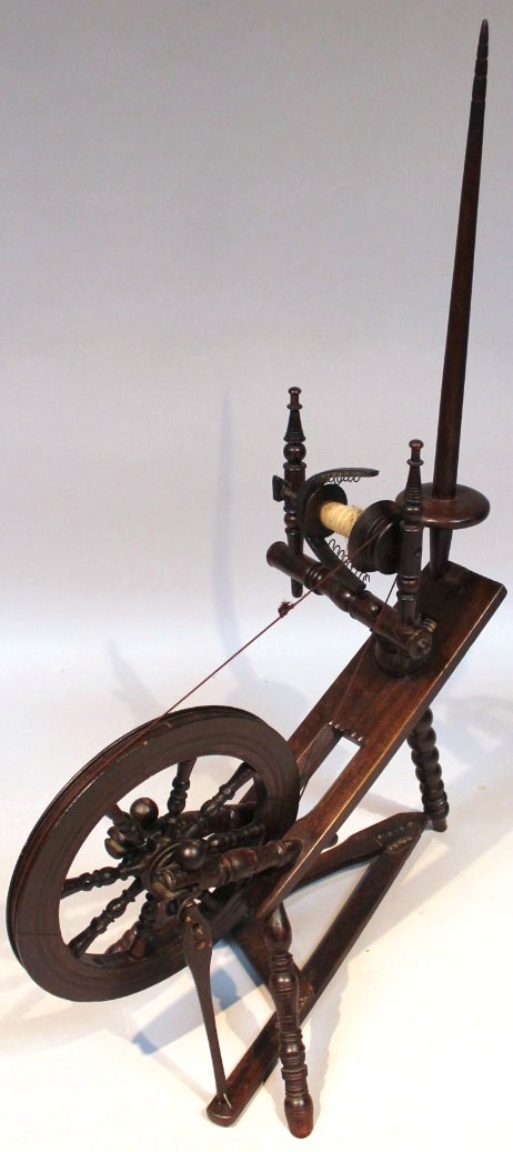 A 20thC stained beech spinning wheel, with a tapering pommel and articulated reel attached to a