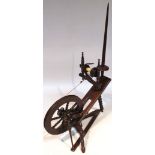 A 20thC stained beech spinning wheel, with a tapering pommel and articulated reel attached to a