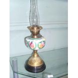 Ornate oil lamp with coloured glass bowl on circular brass and ebonised plinth