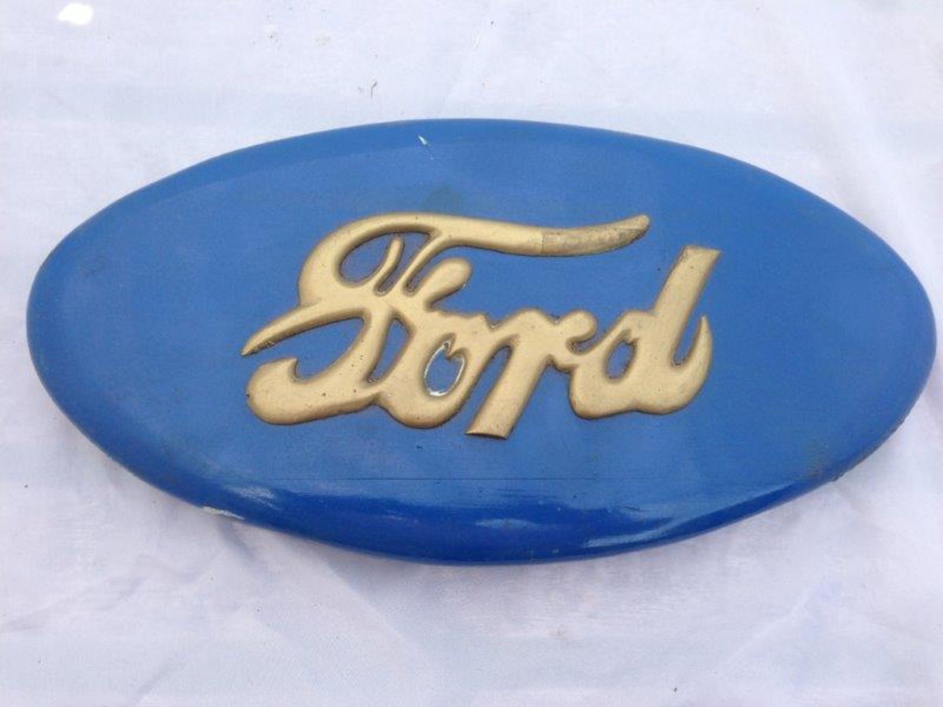 A Ford oval painted wooden plaque.