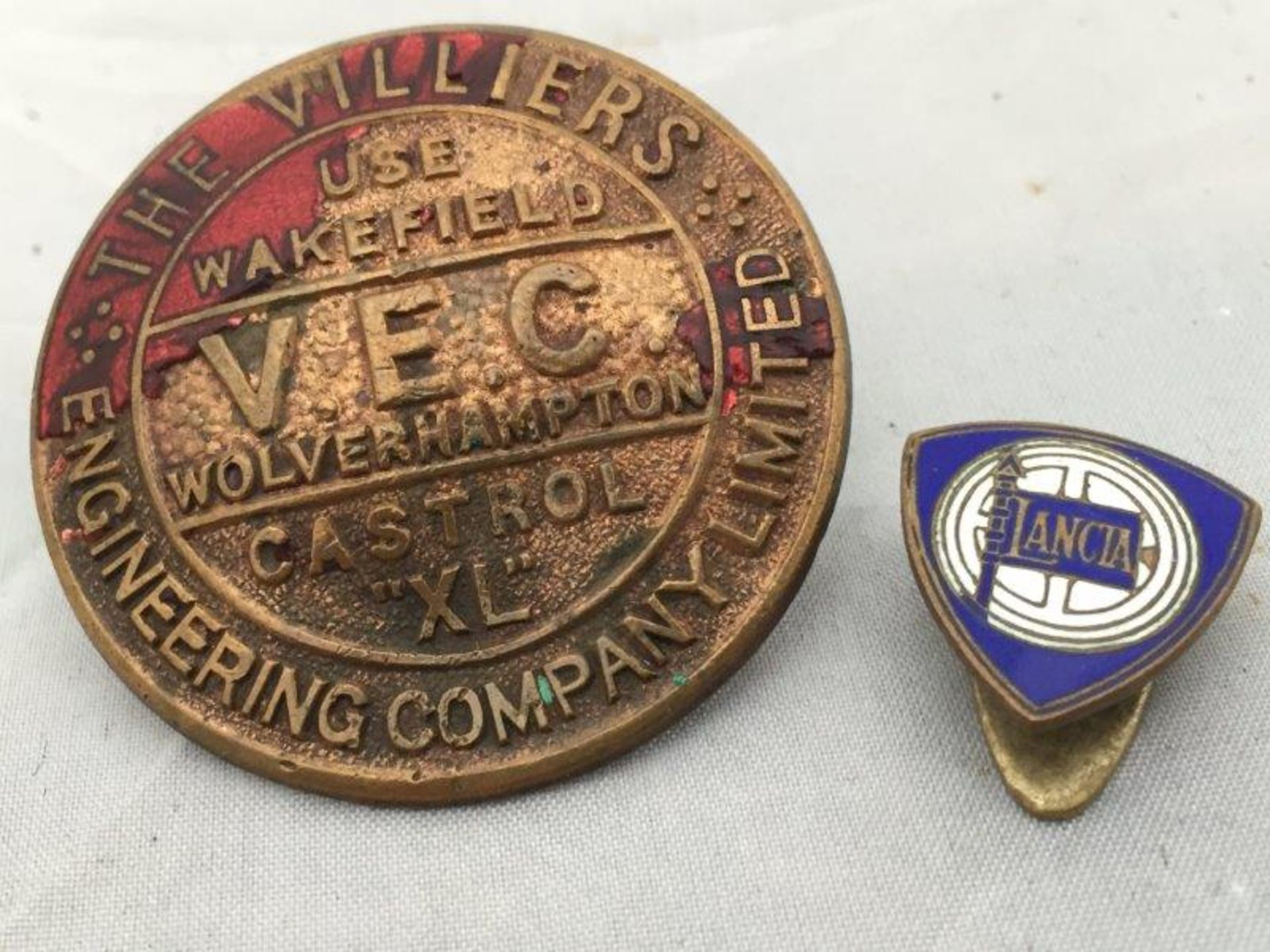 A Wakefield Castrol VEC Motor Oil badge clip together with a Lancia Motor Car enamel lapel badge.