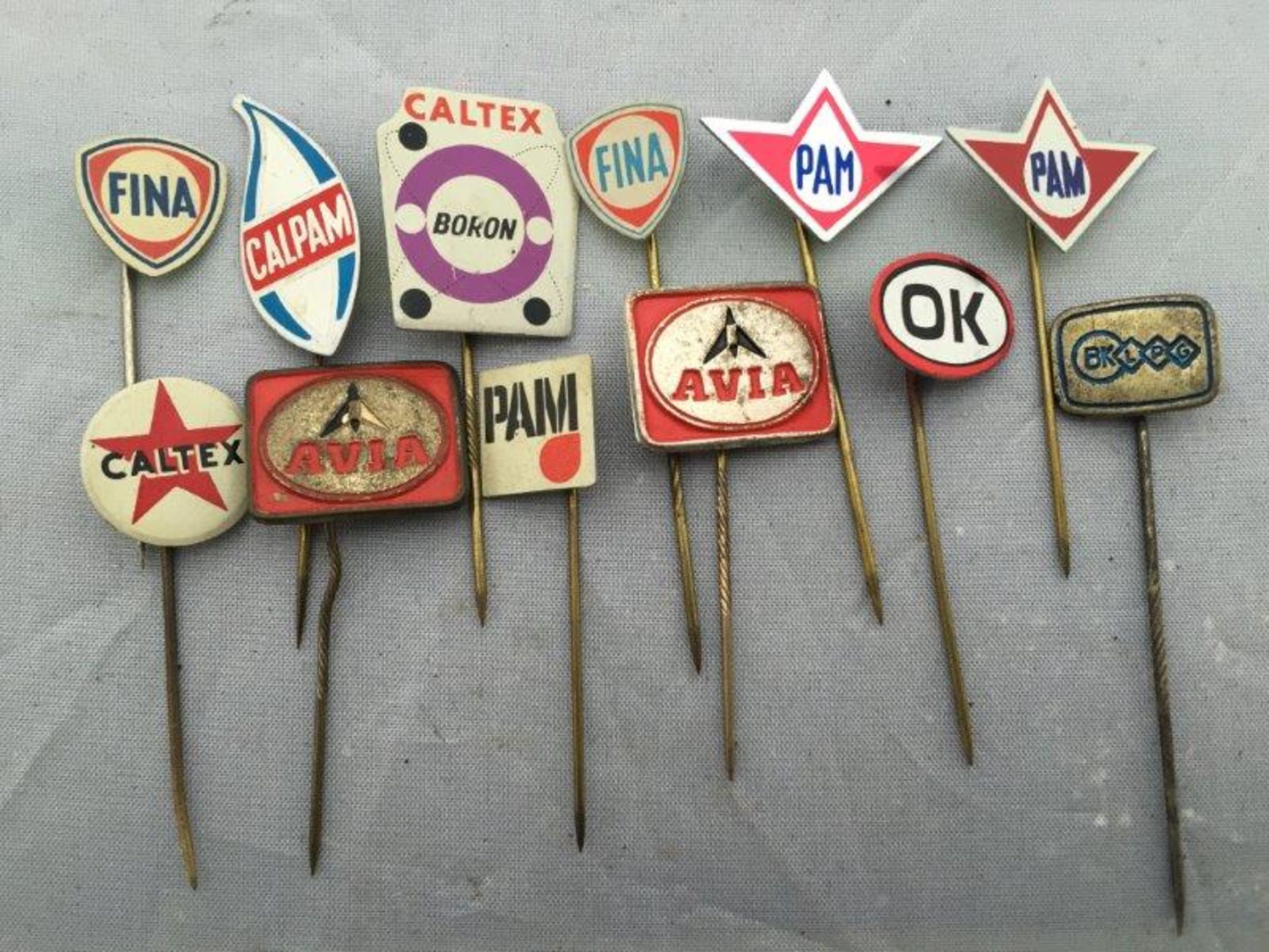 A collection of 12 petrol and oil motoring stick pins including Fina and Caltex.