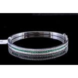 Emerald and diamond bangle, central row of square cut emeralds, estimated total emerald weight 1.