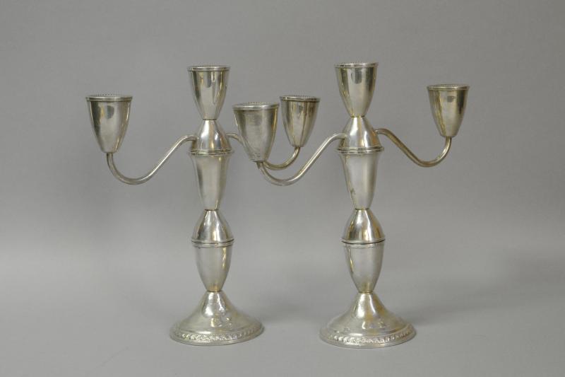 *A pair of white metal three branch candelabra, marked ' Sterling', 25.6cm high, filled (Lot subject