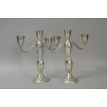 *A pair of white metal three branch candelabra, marked ' Sterling', 25.6cm high, filled (Lot subject
