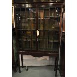 An Edwardian mahogany display cabinet with two glazed doors enclosing adjustable shelves, above a