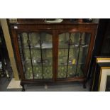 An Edwardian bow fronted display cabinet with Art Nouveau astragal doors, on claw and ball feet,