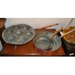 A copper seven egg poacher together with three copper frying pans
