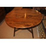 An Ercol dark elm circular drop flap dining table, 125cm diameter