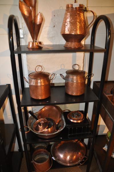 Four shelves containing a good quantity of hammered copper including; storage jars, flower holder