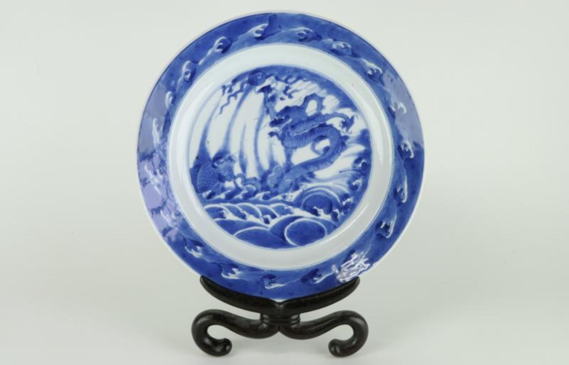 A Chinese Kangxi marriage plate painted with a dragon and a carp leaping from the waves, within a