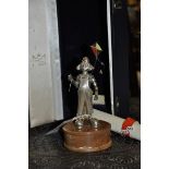 A silver statuette of a clown flying an enamelled kite by Eaton and Jones, mounted on an oak base,