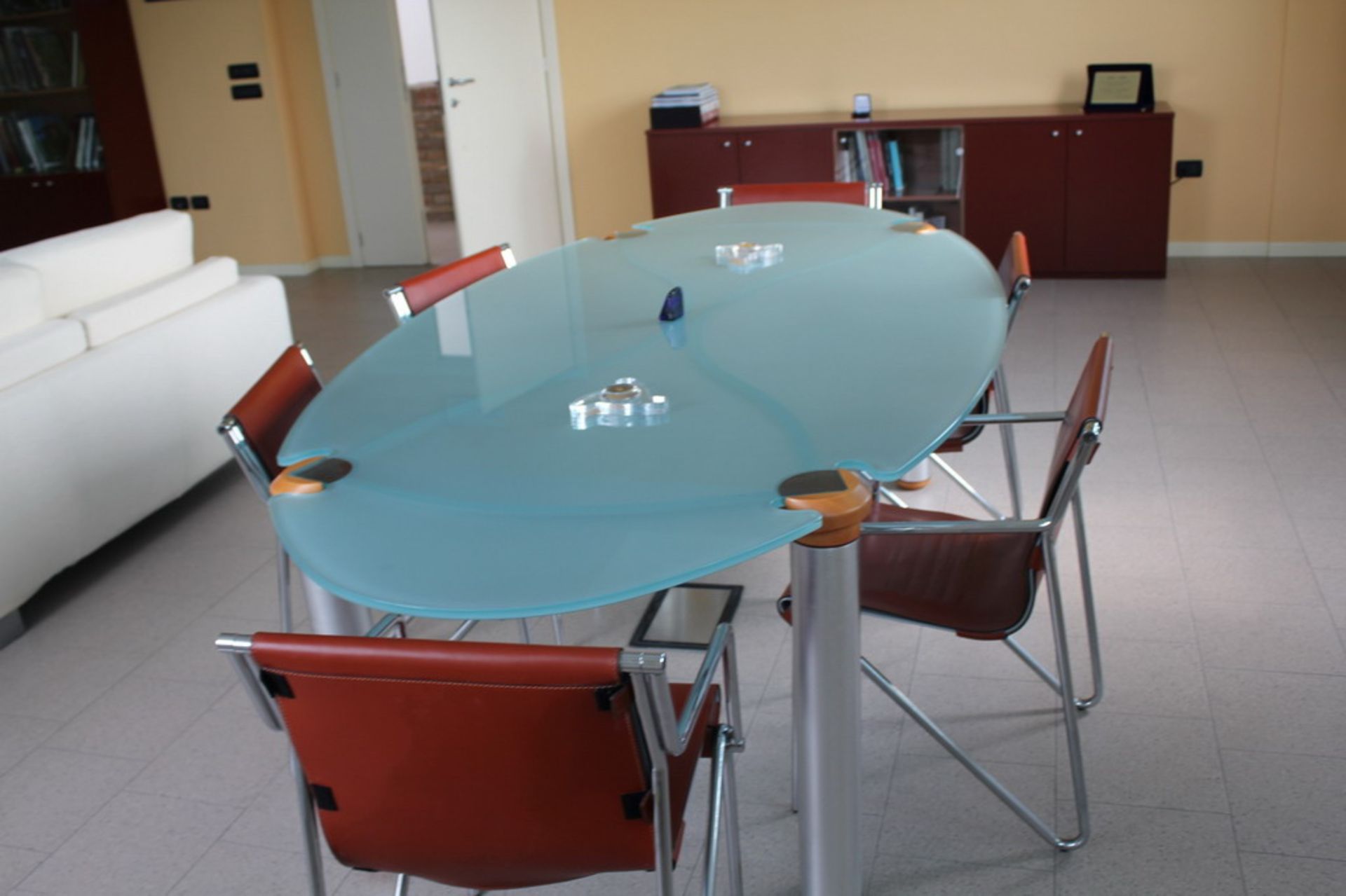 Tavolo riunioni ovale in vetro e metallo con sei sedie in similpelle e metallo