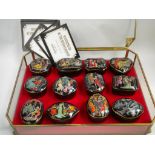 A set of twelve Franklin Mint Russian lacquer style china music boxes in a display case.