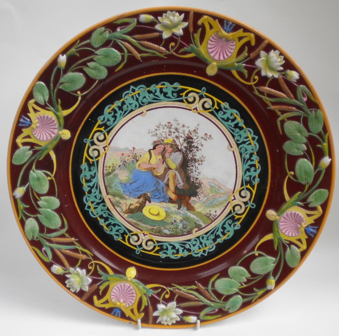 A Villeroy and Boch large majolica charger with water lily and bulrush border and romantic scene