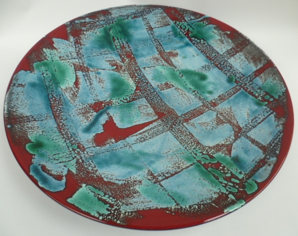 A large Poole Pottery charger from the Delphis range decorated with deep turquoise and burgundy