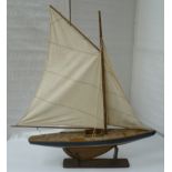 A painted wooden model gaff rigged sail boat.