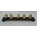 Five various early 20th century carved ivory okimonos on a wooden stand, each figure 5cm tall