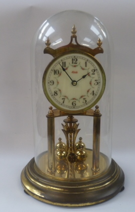 A two train cuckoo clock and a brass 400 day mantel clock contained within a glass dome.