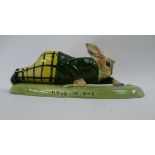 An Acorn china figurine depicting a golfing rabbit lying prone on a green base inscribed ''Hole in