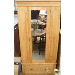 A Victorian stripped pine single wardrobe fitted with a mirrored door over one long drawer.