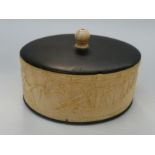 An Egyptian revival oval carved ivory trinket box with ebony base and cover (age complies with CITES