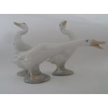 Three small Lladro goose figures.