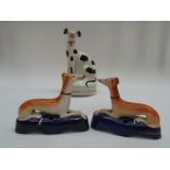 A pair of Staffordshire pen holders in the form of reclining greyhounds and a figure of a seated