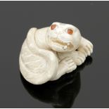 NetsukeJapan, 19. Jahrhundert. - Fo-Hund - Elfenbein. H. 3 cm. Bez. Liegende Figur mit Glasaugen.