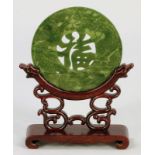 Bi-ScheibeChina, 20. Jahrhundert. Jade auf Holzsockel. H. mit Sockel 21 cm. D. 13 cm.