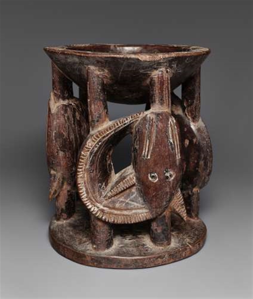 A YORUBA IFA BOWL  Agere ifa, the support carved as three coiled mudfish, dark patina. 20 cm. high
