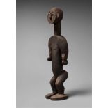 AN IDOMA FIGURE  Standing with arms free of the body, the oval face with features in relief, dark