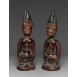 A PAIR OF YORUBA TWIN FIGURES  Ibeji, male, each with tall blackened coiffure, beads about the