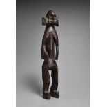A MUMUYE FIGURE  Standing with arms carved free of the body, the eyes and scarified cheeks