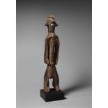 A MUMUYE FIGURE  With highly stylised face and median crested coiffure, dark patina. 55 cm.