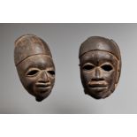 TWO YORUBA EGUNGUN MASKS Each with sensitively carved features and pierced eyes, one with smooth