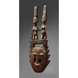 A YORUBA MASK Oloju Foforo, the face with pierced rectangular eyes and serrated border, surmounted