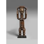 AN ATTIE FIGURE The standing female with the arms raised holding a container on top of the head,