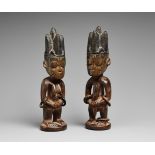 A PAIR OF YORUBA TWIN FIGURES Male and female, each with the hands on the abdomen, the blackened