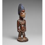 A YORUBA MALE TWIN FIGURE With blued, cap-like coiffure, carved amulet on the chest, prominent