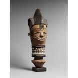 A KUYU HEAD With carved filed teeth in the mouth, incised blackened coiffure, scarification to