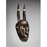 A MALINKE MASK The face with inset metal teeth in the slightly open mouth, pierced eyes, two curving