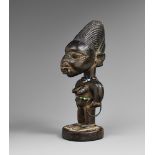 A YORUBA FEMALE TWIN FIGURE With large head, carved teeth in the mouth, beads about the neck and