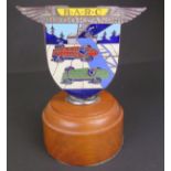 An enamelled Brooklands car badge depicting a green and red racing cars, of shield form and with