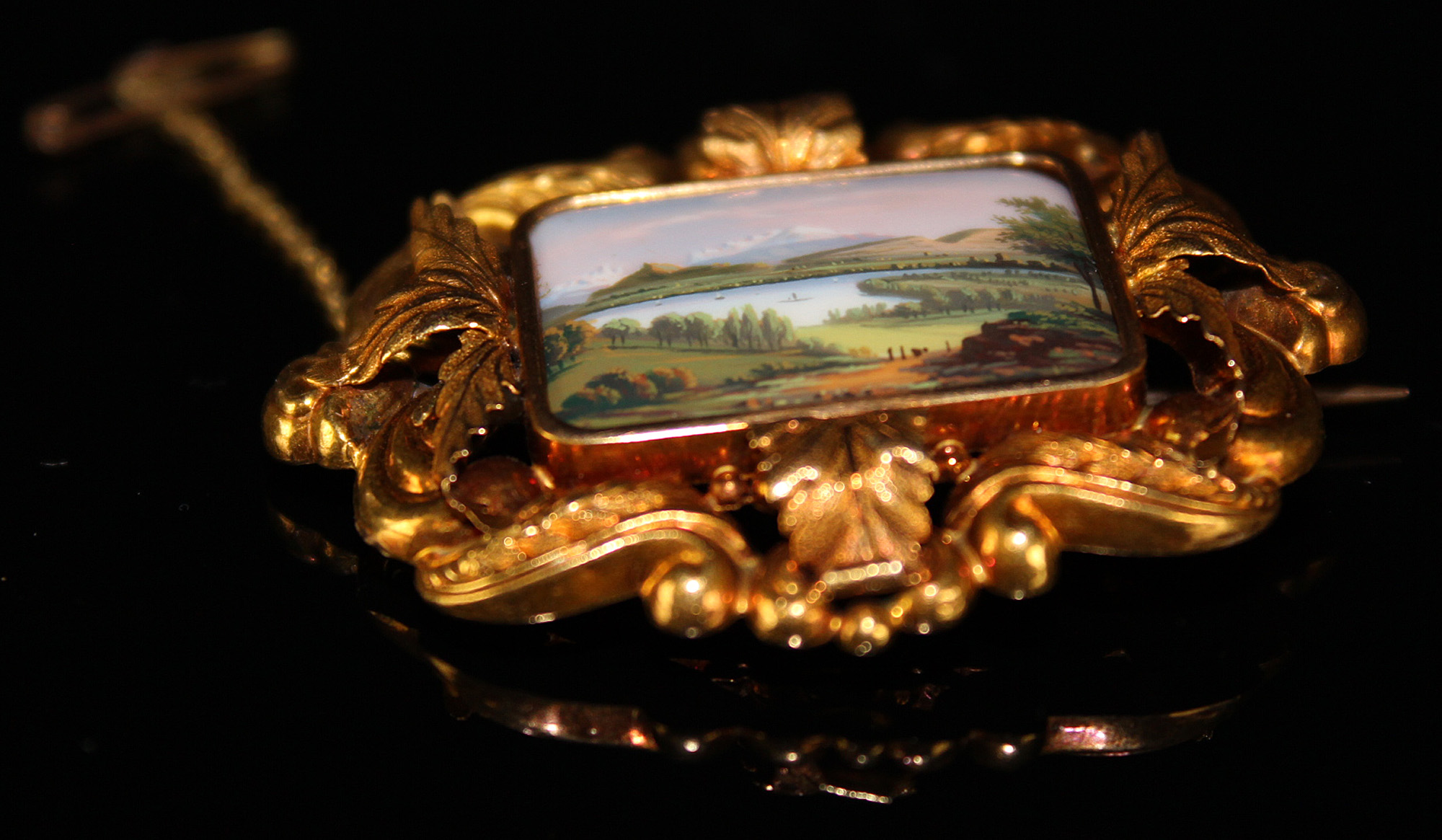 Yellow metal Brooch with safety chain with central enamel plaque depicting a mountain/meadow scene